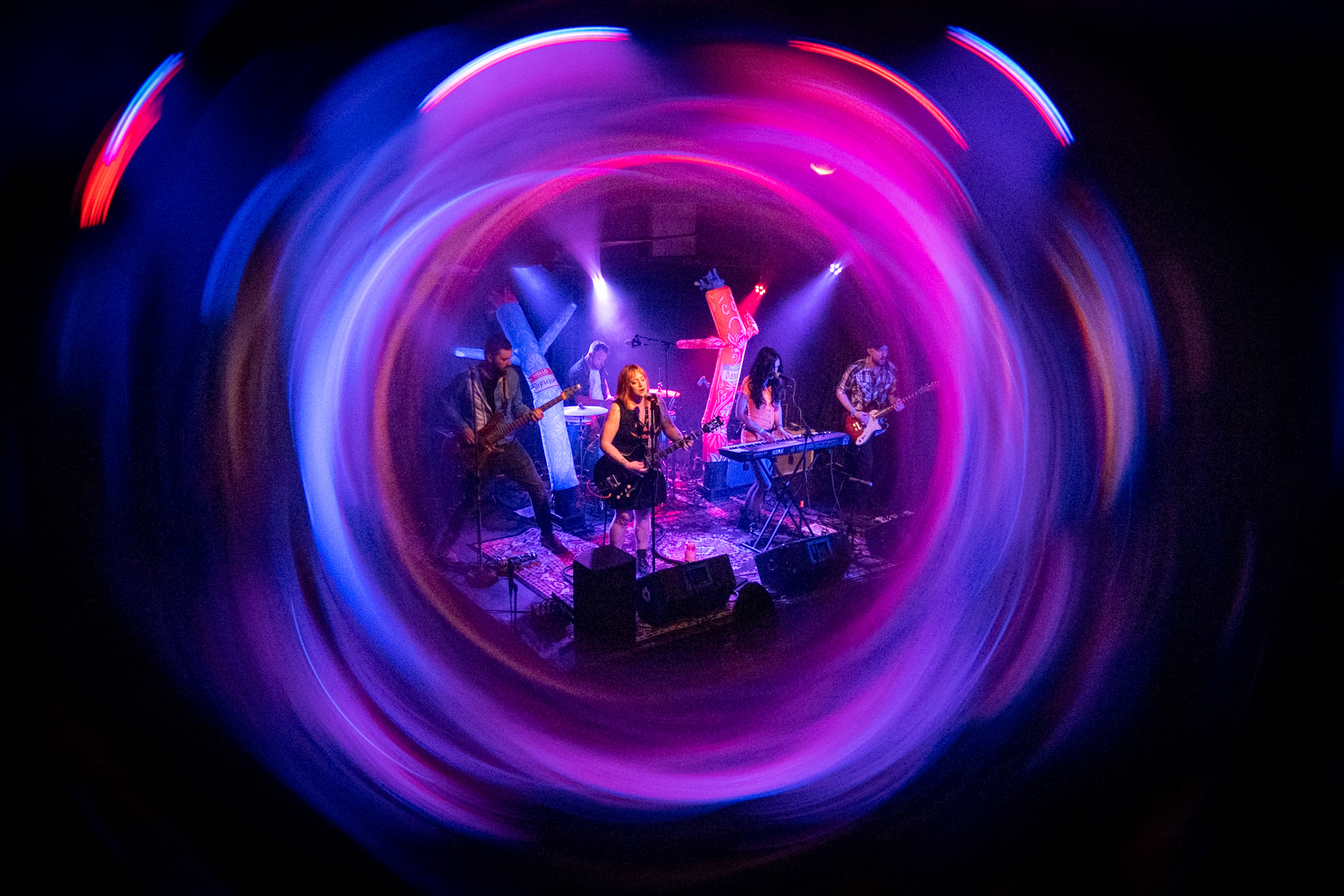 The Cancellations performing live at the East Room, surrounded by a swirl of colorful lights