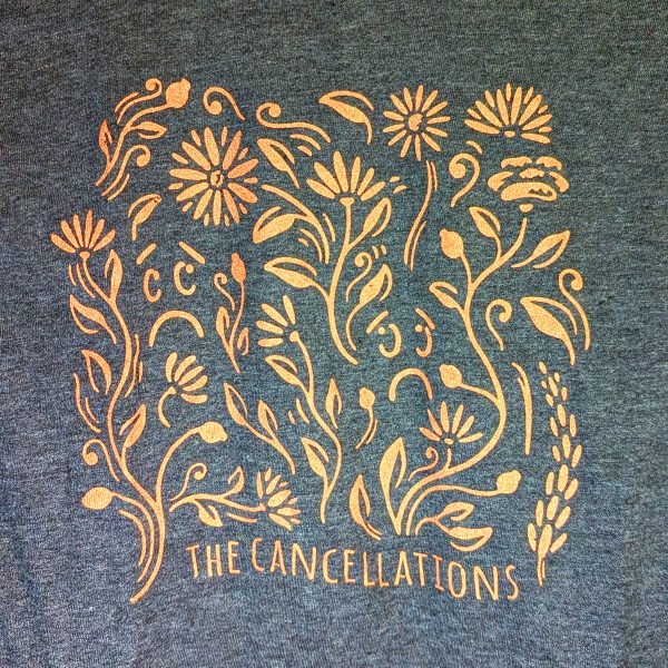 Close-up of the design on The Cancellations' "Garden Secrets" t-shirt. It features a swirly floral print with Depression and Dance's faces mixed in. At the bottom it reads "The Cancellations" in all caps.