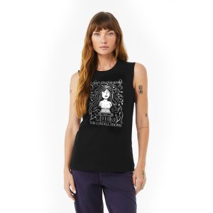 A fair skinned brunette woman wearing a black muscle tank with The Cancellations' "Smile" art printed on it